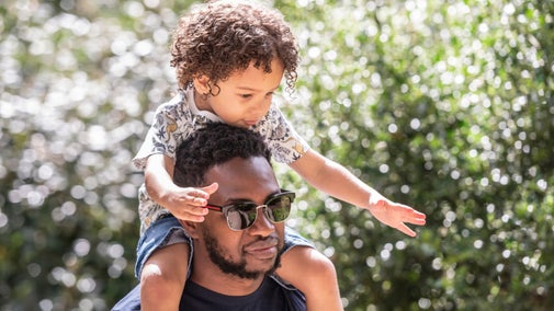 Father and son pictured on a sunny day, white flowers in the background.